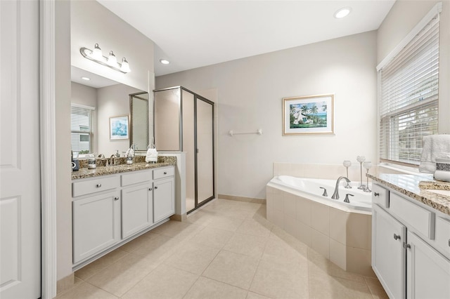 bathroom featuring two vanities, plenty of natural light, a shower stall, and a bath