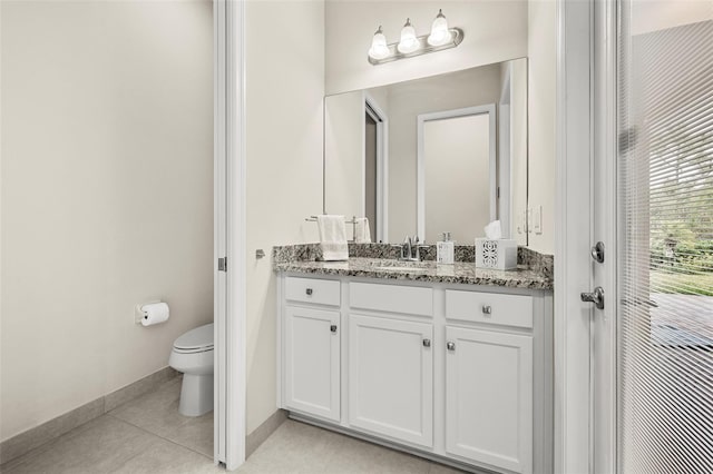 bathroom featuring toilet, vanity, baseboards, and tile patterned floors