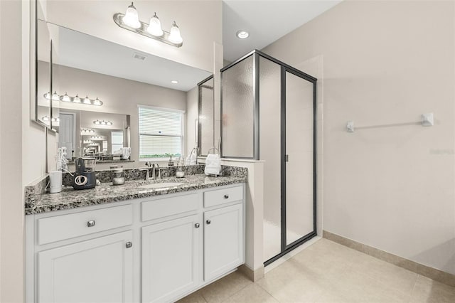 bathroom with a stall shower, vanity, baseboards, and tile patterned floors