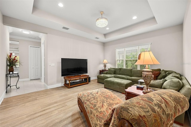 living area with a tray ceiling, recessed lighting, visible vents, light wood-style floors, and baseboards