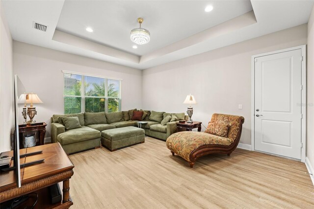 living area featuring a tray ceiling, visible vents, recessed lighting, and wood finished floors