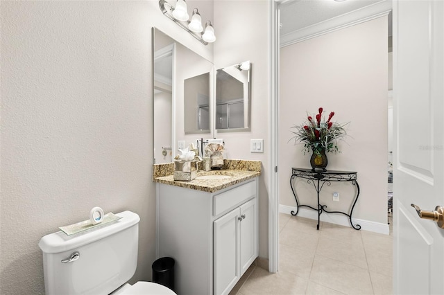 bathroom with crown molding, toilet, vanity, baseboards, and tile patterned floors