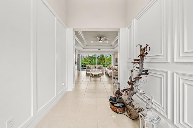 hall with light tile patterned floors, a decorative wall, and crown molding