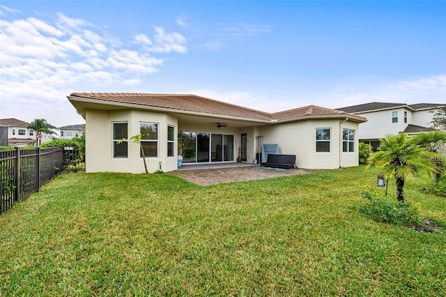 back of property with a fenced backyard, ceiling fan, a lawn, and a patio