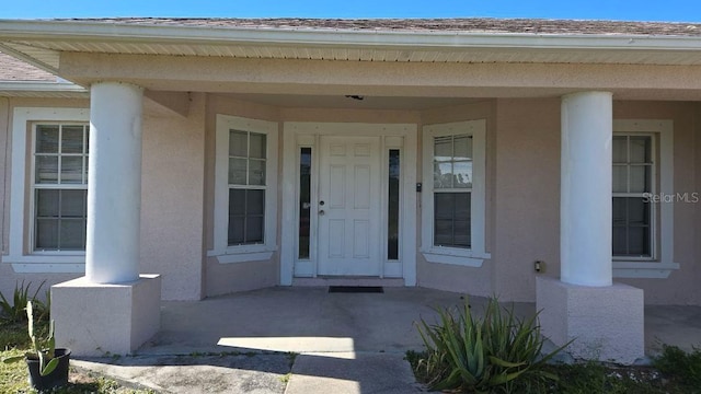 property entrance with roof with shingles and stucco siding