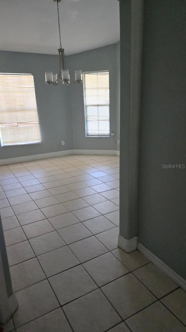 tiled empty room with vaulted ceiling and a chandelier