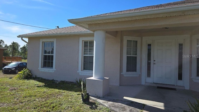 view of exterior entry featuring a yard and stucco siding