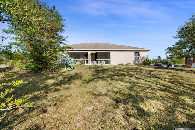 915 Poinsettia Ave, Lehigh Acres, FL 33972 - back of property with a sunroom, a lawn, and stucco siding
