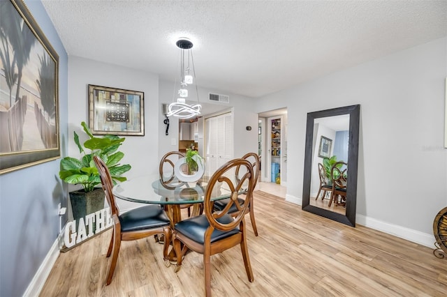 dining space featuring light hardwood / wood-style floors and a textured ceiling