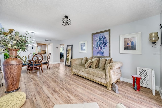 living room featuring light wood-type flooring and a textured ceiling