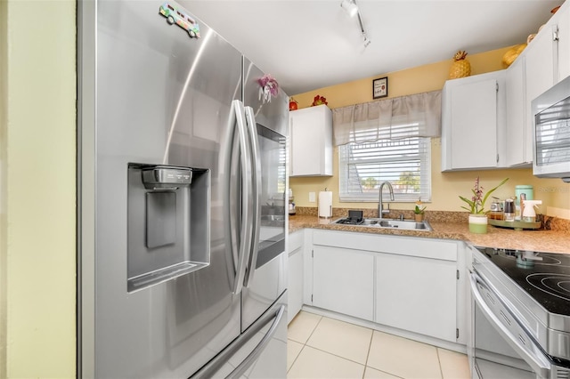 kitchen with white cabinets, stainless steel appliances, sink, rail lighting, and light tile patterned floors