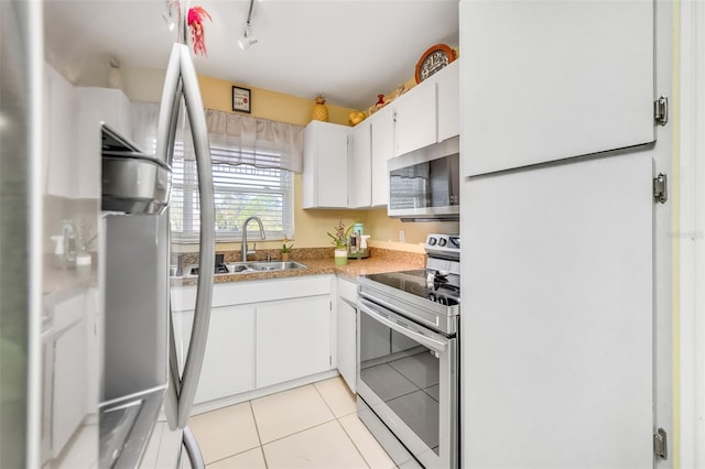 kitchen with sink, light tile patterned flooring, white cabinetry, appliances with stainless steel finishes, and rail lighting