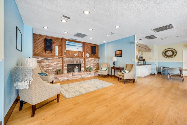 living room featuring a textured ceiling, light hardwood / wood-style floors, and a fireplace