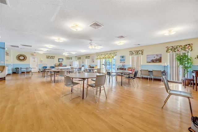 dining space with a textured ceiling, ceiling fan, and light hardwood / wood-style flooring