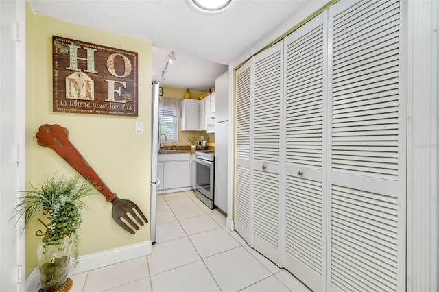 hall with sink, light tile patterned flooring, and a textured ceiling