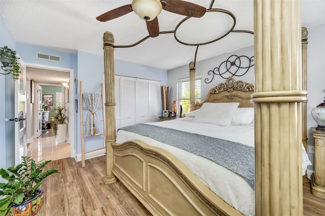 bedroom with ceiling fan, a textured ceiling, a closet, and light hardwood / wood-style flooring