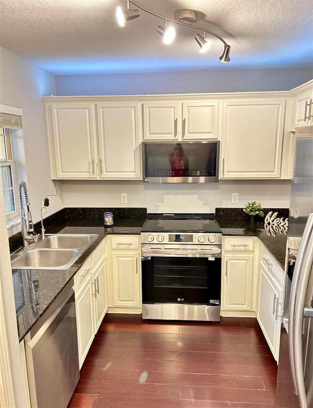 kitchen with dark wood-type flooring, sink, a textured ceiling, track lighting, and appliances with stainless steel finishes