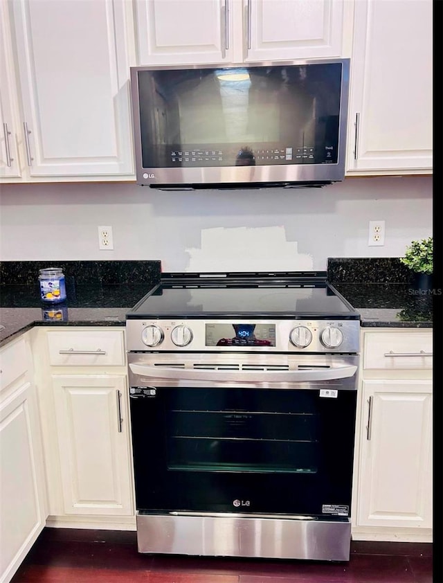 kitchen with stainless steel appliances, white cabinets, and dark stone counters