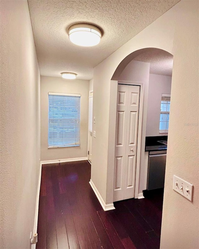 hall with dark wood-type flooring and a textured ceiling