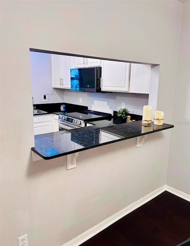 kitchen with stainless steel appliances, white cabinetry, a kitchen breakfast bar, and kitchen peninsula