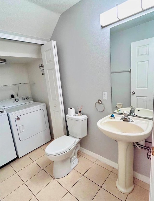 bathroom with washer and clothes dryer, a textured ceiling, vaulted ceiling, tile patterned floors, and toilet