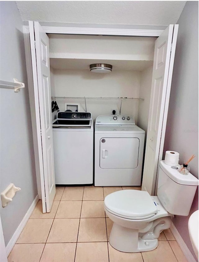 bathroom featuring tile patterned flooring, washer and dryer, and toilet