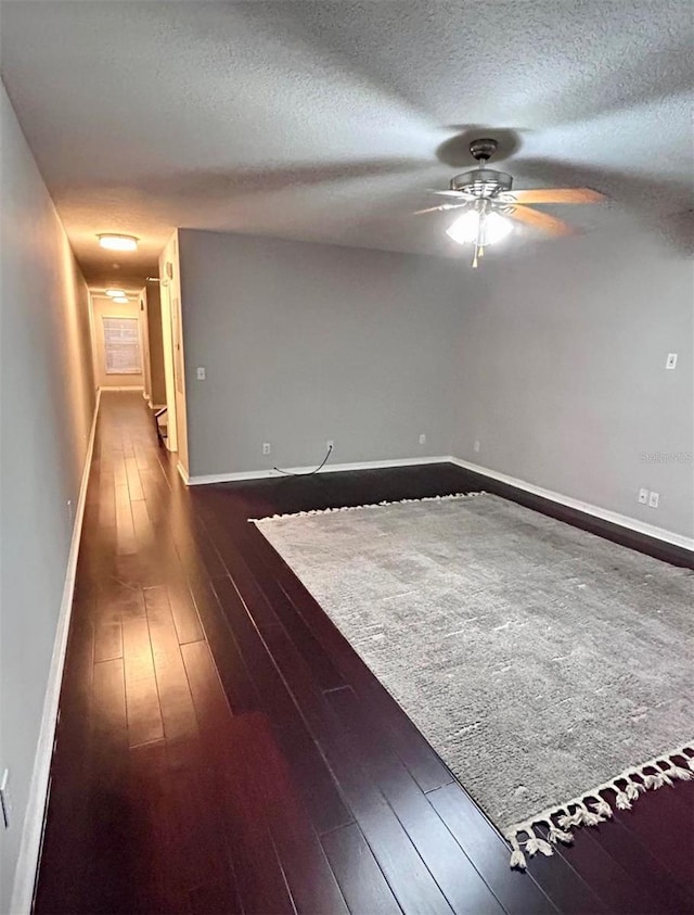 unfurnished room with ceiling fan, dark wood-type flooring, and a textured ceiling