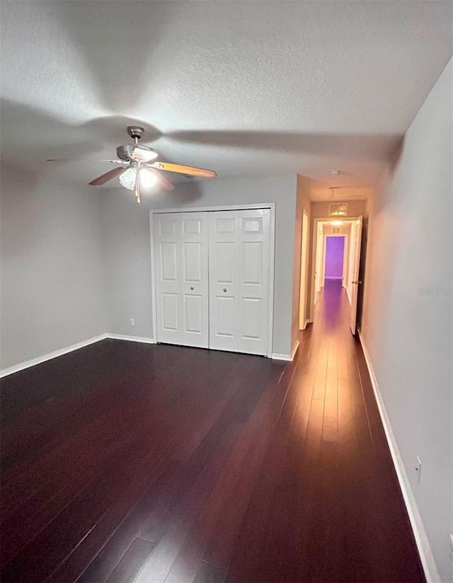 unfurnished bedroom with ceiling fan, dark hardwood / wood-style floors, a closet, and a textured ceiling