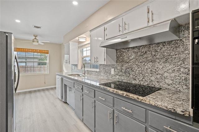 kitchen featuring sink, stainless steel refrigerator, plenty of natural light, tasteful backsplash, and black electric stovetop