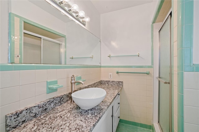 bathroom featuring tile walls, vanity, and a shower with door