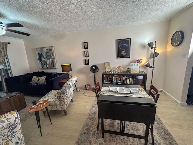 living room with ceiling fan, a textured ceiling, and light wood-type flooring