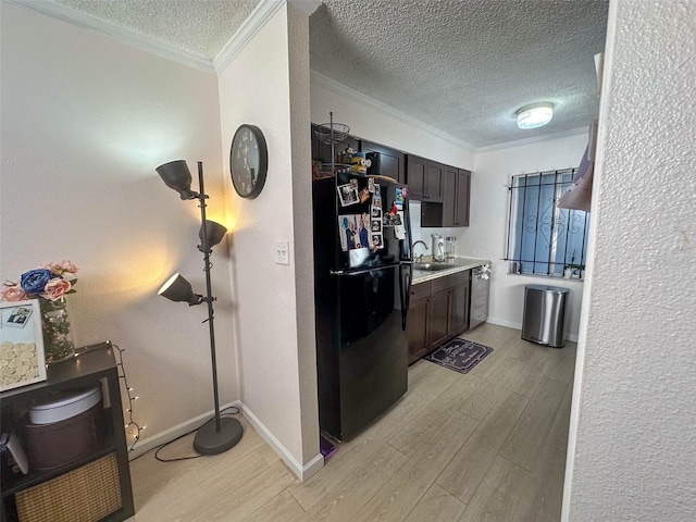 kitchen featuring dark brown cabinets, sink, black fridge, and crown molding