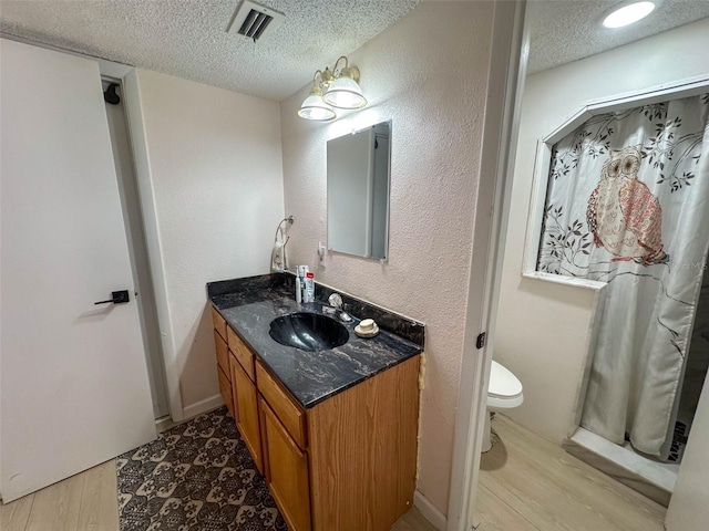 bathroom featuring toilet, vanity, a textured ceiling, and hardwood / wood-style floors