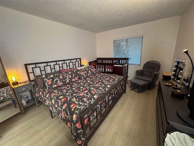 bedroom featuring light hardwood / wood-style floors and a textured ceiling