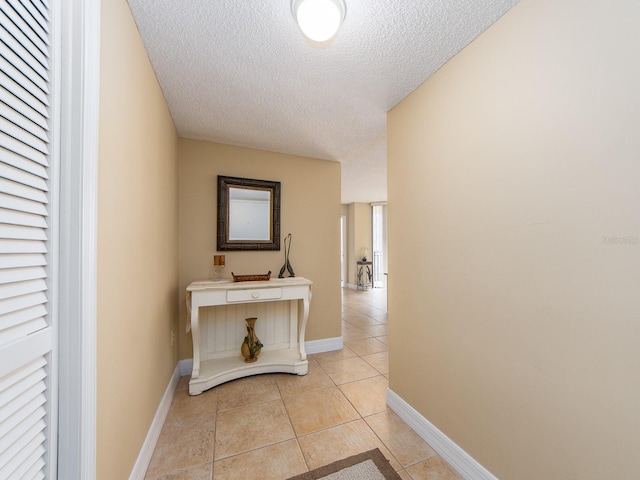 hall featuring a textured ceiling and light tile patterned floors