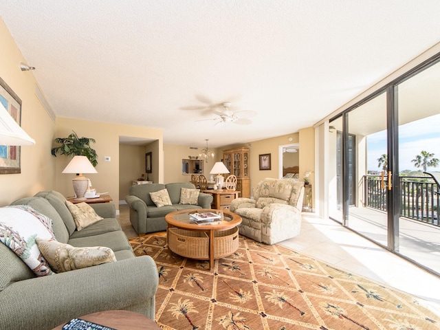 living room featuring tile patterned flooring, ceiling fan with notable chandelier, and a wall of windows