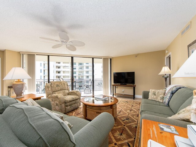 living room featuring ceiling fan, floor to ceiling windows, and a textured ceiling