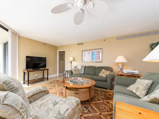 living room featuring ceiling fan and a textured ceiling