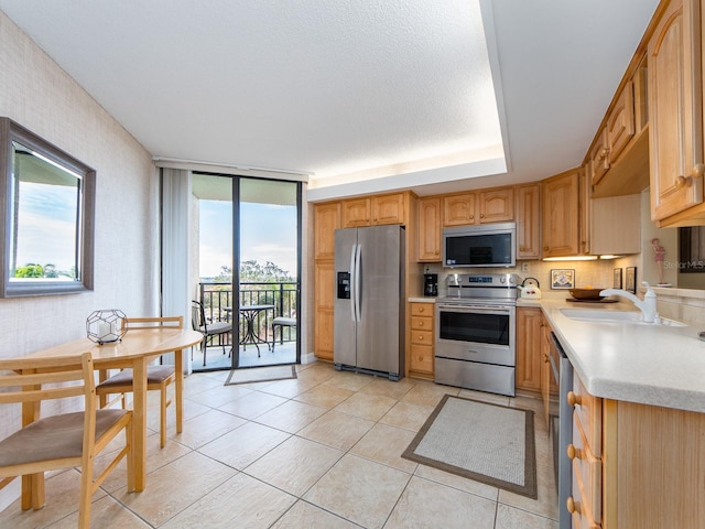 kitchen featuring stainless steel appliances, expansive windows, a healthy amount of sunlight, and light tile patterned floors