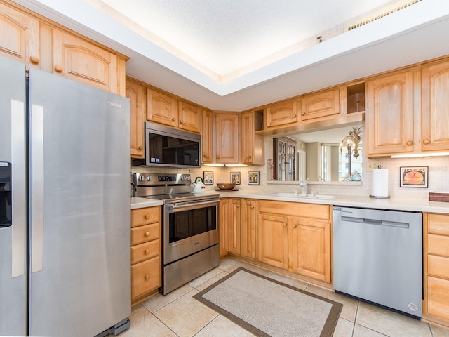 kitchen with light tile patterned flooring, light brown cabinetry, sink, decorative backsplash, and stainless steel appliances