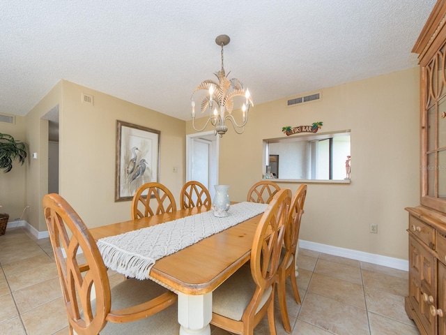 dining space with a notable chandelier, a textured ceiling, and light tile patterned floors