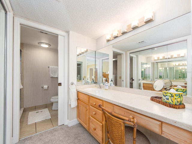 bathroom with tile patterned floors, toilet, vanity, and a textured ceiling