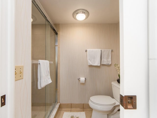 bathroom featuring a shower with door, tile patterned floors, and toilet