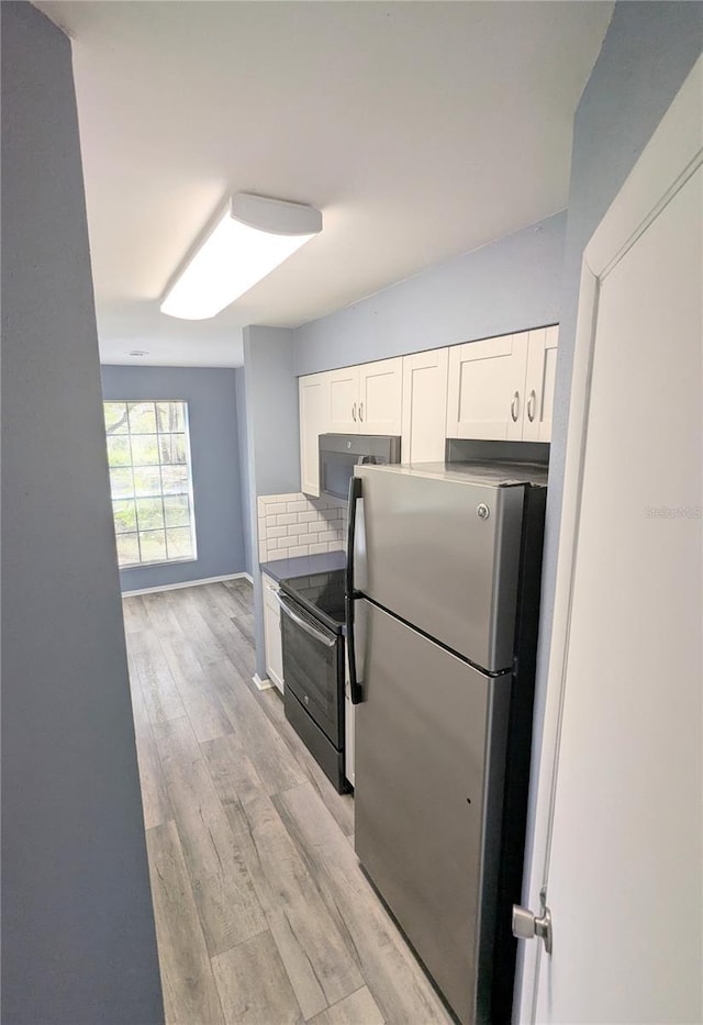 kitchen with decorative backsplash, stainless steel refrigerator, white cabinetry, light hardwood / wood-style flooring, and range with electric cooktop