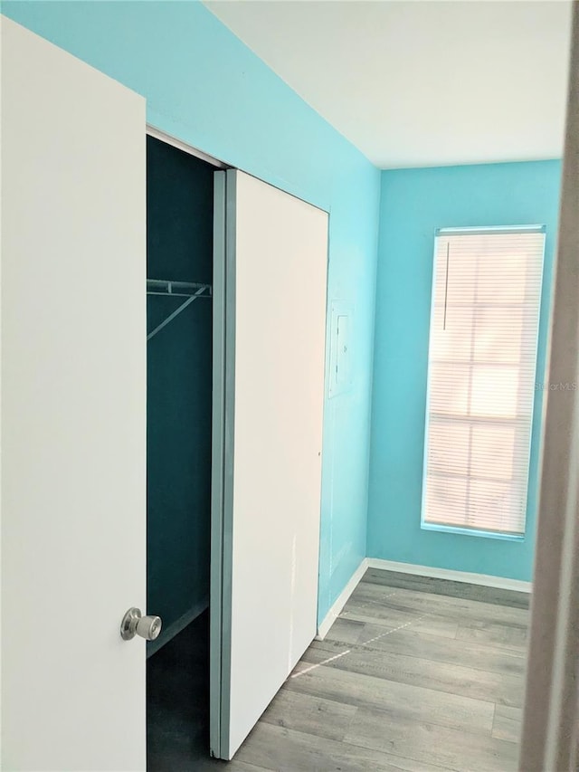 unfurnished bedroom with light wood-type flooring, a closet, and multiple windows