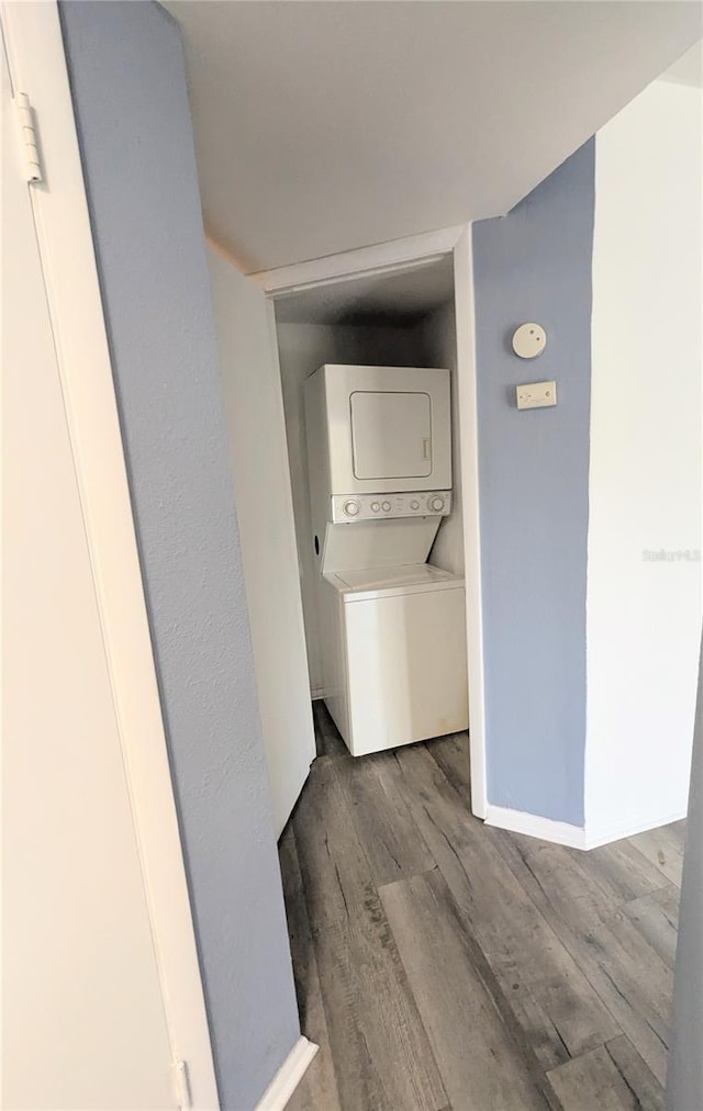 clothes washing area featuring stacked washer / drying machine and hardwood / wood-style flooring