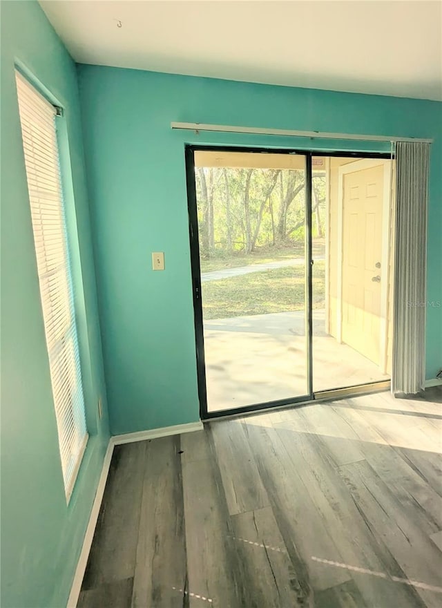 doorway to outside featuring baseboards and wood finished floors