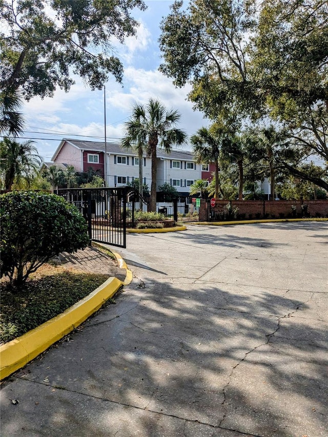view of road with a gated entry, curbs, a gate, and traffic signs