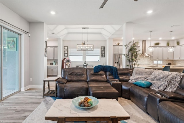 living room featuring plenty of natural light, sink, an inviting chandelier, and light hardwood / wood-style floors