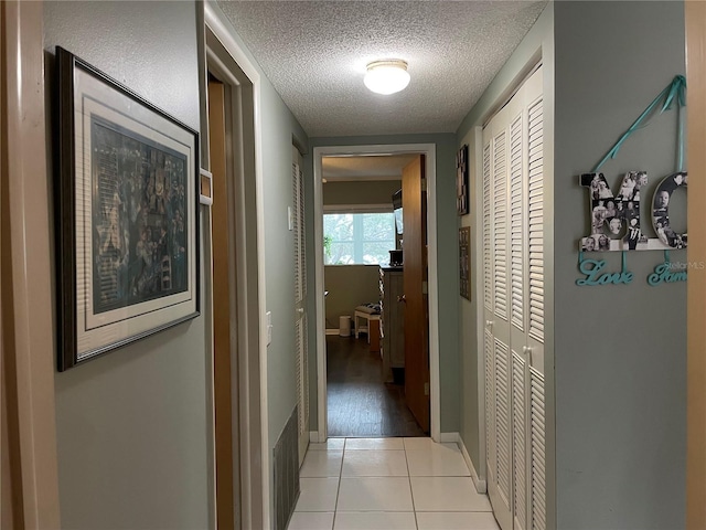 corridor featuring light tile patterned floors and a textured ceiling